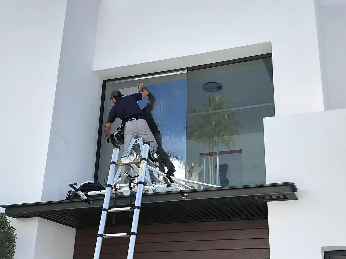 Exterior reflective window film being installed on tall villa glazing in Benahavís