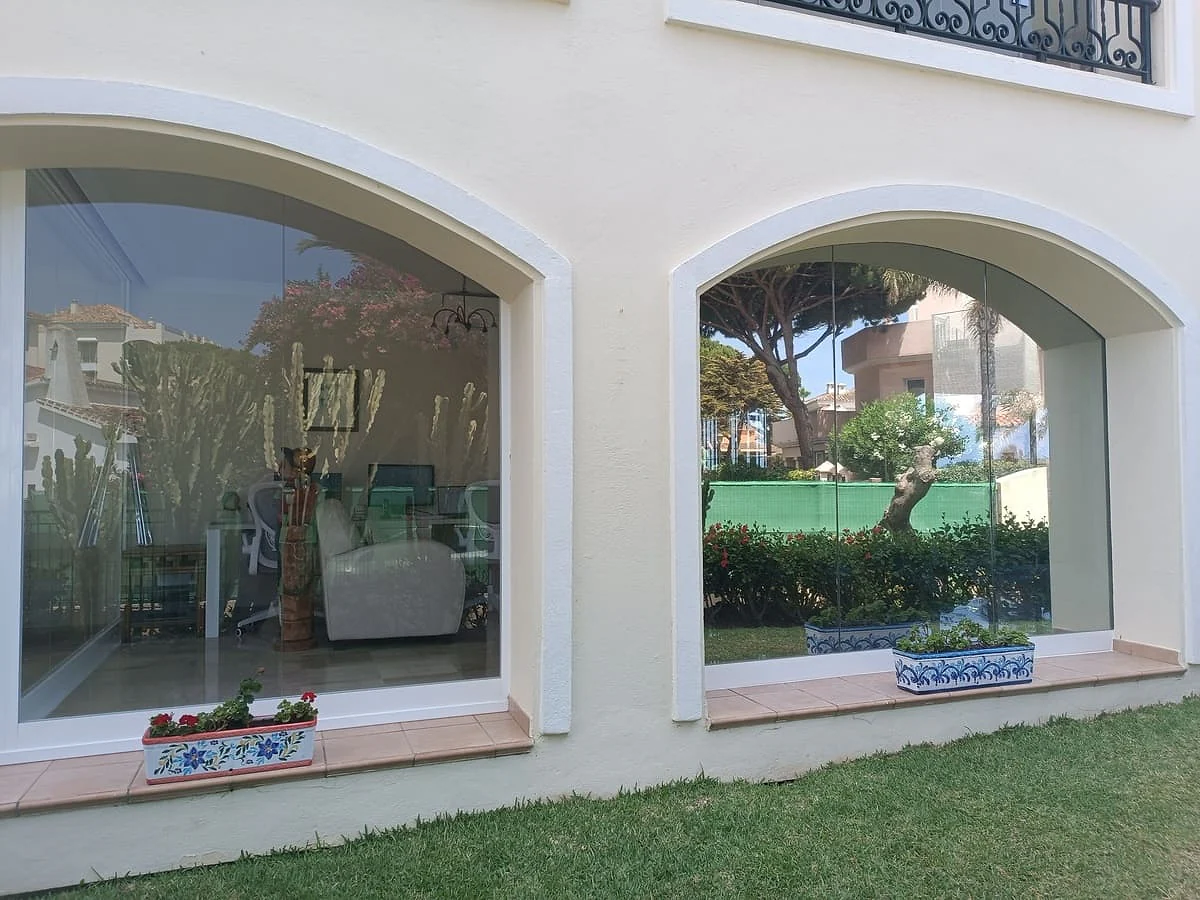 One-way view privacy film on the arched windows of a villa, reflecting the garden
