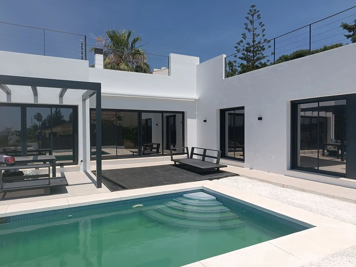 Solar control film on the black-framed glazing of a modern Marbella villa, seen across the pool